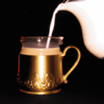 fotografia sobre la importancia de una buena jarra para espumar la leche en tu cafe para portada de una categoria en una pagina web sobre cafe y cafe expresso y utiliza mucho el color oro b89634 y