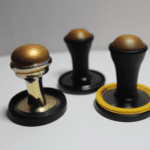 fotografia sobre los tamper mas ligeros y faciles de manejar para un uso diario para portada de una categoria en una pagina web sobre cafe y cafe expresso y utiliza mucho el color oro b89634 y en m 1