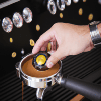 fotografia sobre como inspeccionar la calidad del cafe producido por tu maquina de cafe expresso para portada de una categoria en una pagina web sobre cafe y cafe expresso y utiliza mucho el color oro
