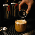 fotografia sobre como preparar un delicioso cafe macchiato en casa para portada de una categoria en una pagina web sobre cafe y cafe expresso y utiliza mucho el color oro b89634 y en menor medida e
