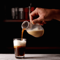 fotografia sobre el arte de preparar un cafe americano con leche para portada de una categoria en una pagina web sobre cafe y cafe expresso y utiliza mucho el color oro b89634 y en menor medida el