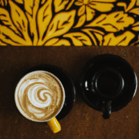 fotografia sobre el arte latte como herramienta de marketing para cafeterias para portada de una categoria en una pagina web sobre cafe y cafe expresso y utiliza mucho el color oro b89634 y en meno