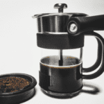 fotografia sobre la aeropress la cafetera para los aventureros del cafe para portada de una categoria en una pagina web sobre cafe y cafe expresso y utiliza mucho el color oro b89634 y en menor me